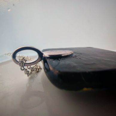 Showing a bail and chain on the back of a fused glass pendant.