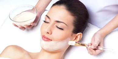 a person applying a mask on the face of a woman