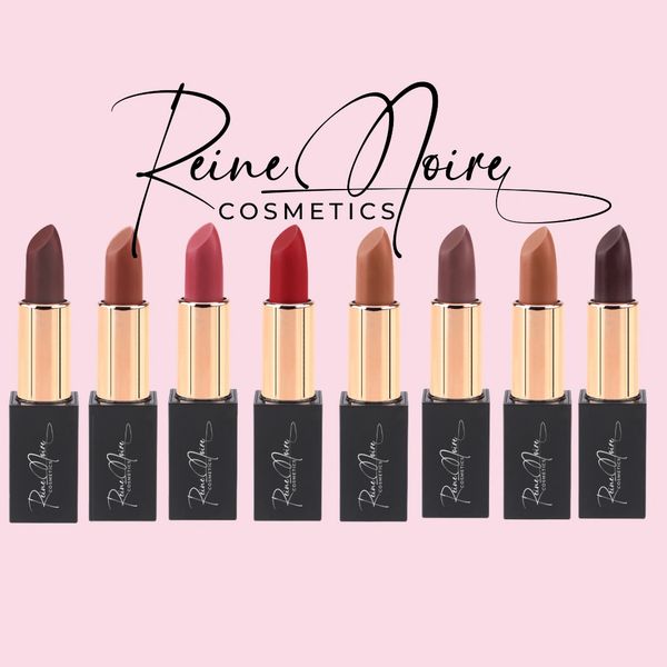 Eight lipsticks in various shades from Reine Noire Cosmetics on a pink background.