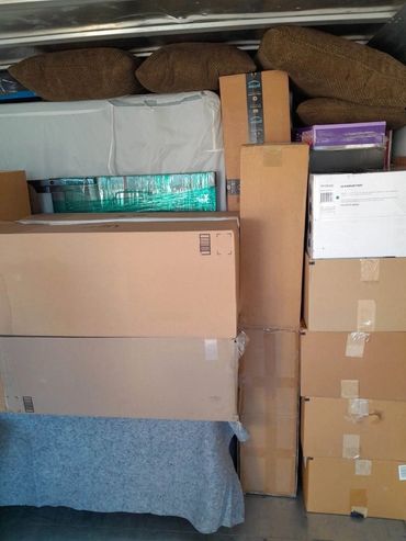 Stacked cardboard boxes and cushions packed in a vehicle.