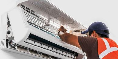 Technician repairing a wall-mounted air conditioner unit.