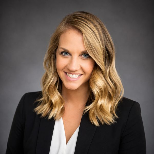 Professional woman with blonde hair smiling in a black blazer.