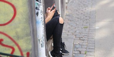 Young girl sitting in doorway looking at phone