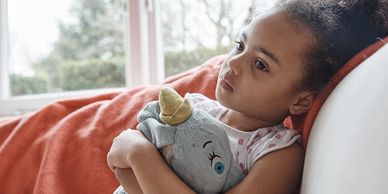 Young minority girl looking depressed holding toy