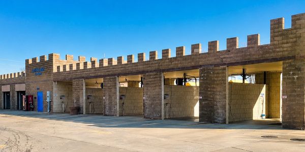 Car wash with multiple washing bays under clear blue sky.