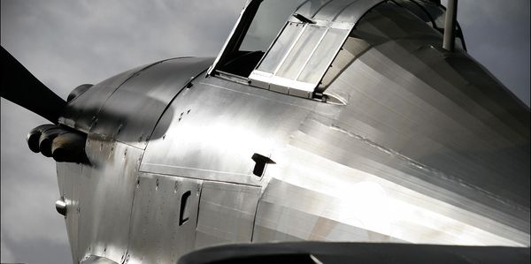 Close-up of a vintage military aircraft's cockpit and fuselage under dramatic lighting.