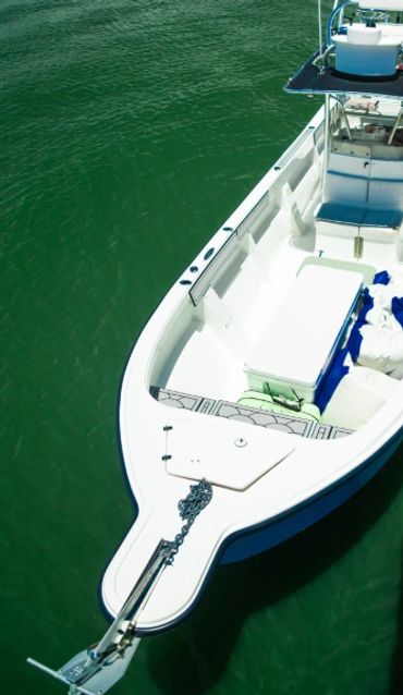 A white fishing boat docked at a pier on calm green waters.