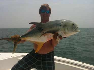 Man holding a large fish on a boat in the ocean.