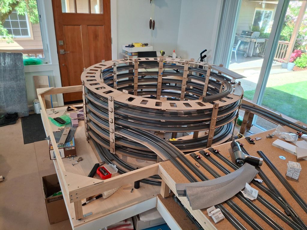 Intricate spiral model train track under construction indoors.