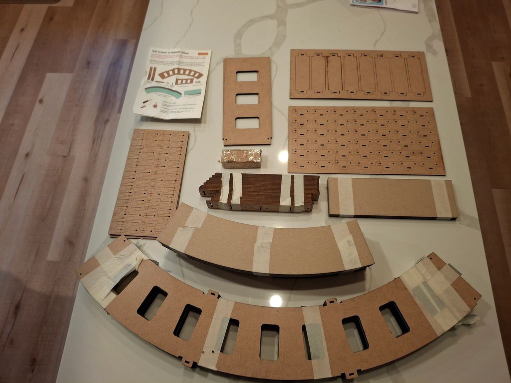 Unassembled wooden train model kit parts on a table.