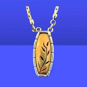 Elegant pendant with leaf engraving on a gold and silver chain.