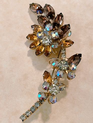 Vintage floral brooch with sparkling rhinestones in amber and clear hues.