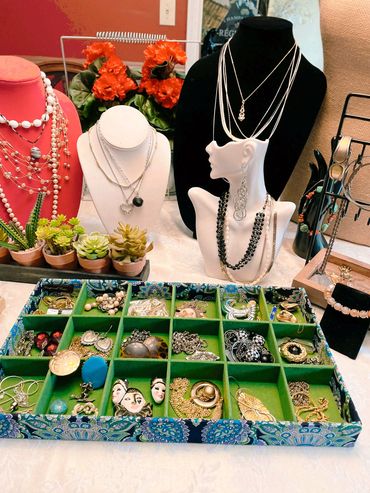A collection of necklaces, earrings, and jewelry displayed with potted succulents.