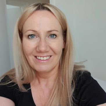 Smiling woman with blonde hair in a black shirt.