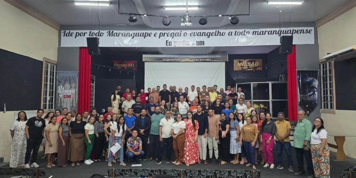 Large group photo at a religious event with a banner in Portuguese.