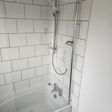 A new electric shower fitted into a bathroom with white tiles