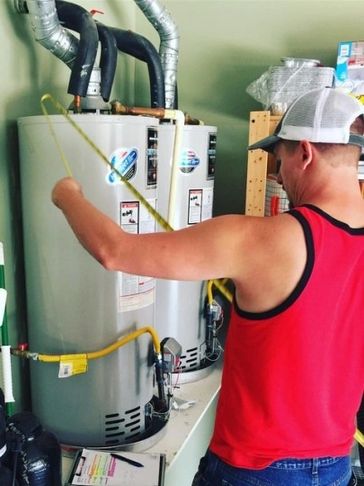 A plumber measures a water heater in the garage