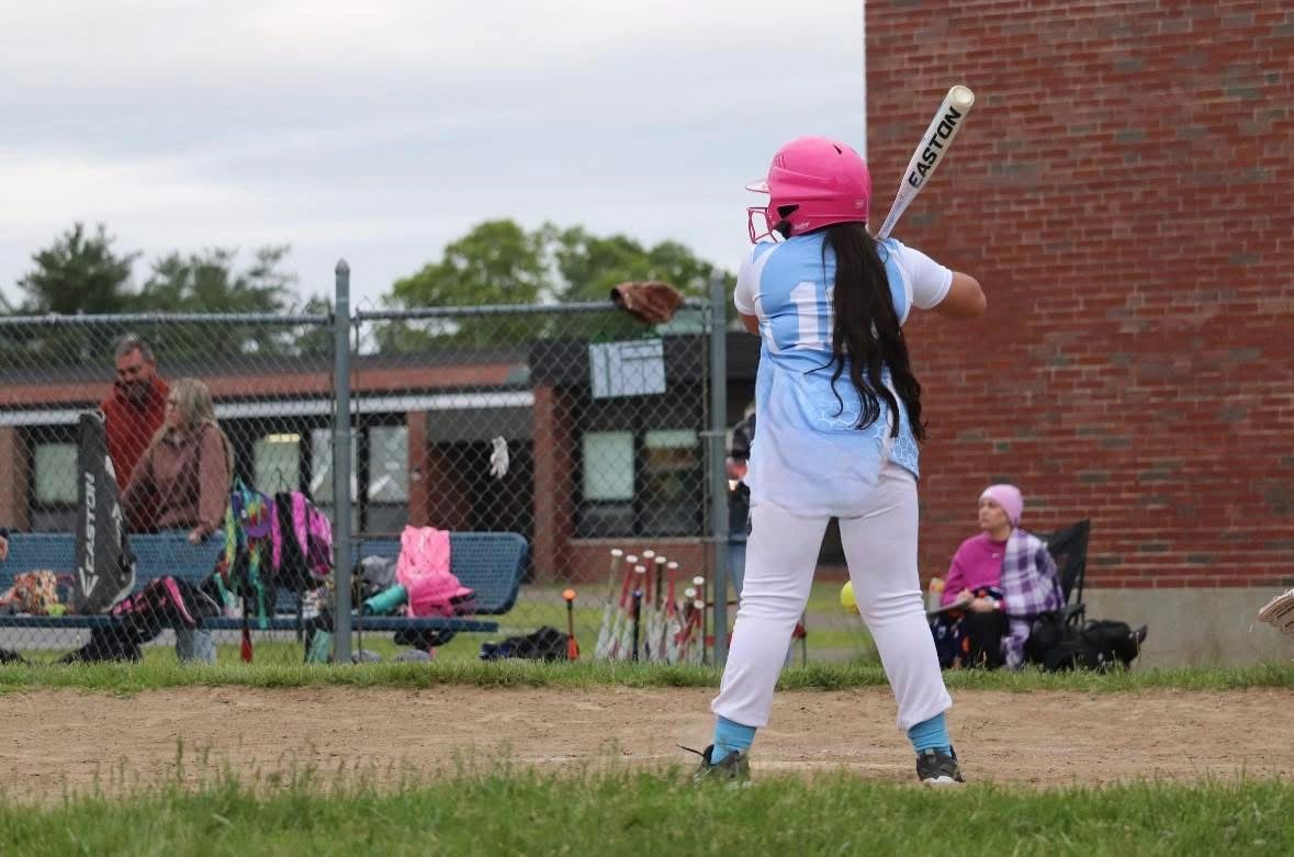 Young baseball player ready to bat on a dirt field.