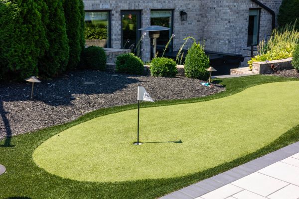 Backyard golf putting green with flag.