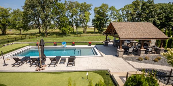 Modern backyard with a pool, lounge chairs, and covered seating area.