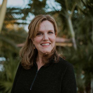 A photo of Ms. Joy, owner of Joy of Therapy, wearing a black zipped-up pull-over, smiling
