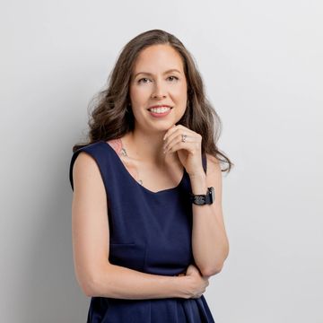A picture of Dr. Sharon Surita, wearing a blue sleeveless dress, smiling