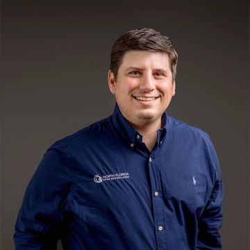 A photo of Dr. Zaideman wearing a blue button down, smiling