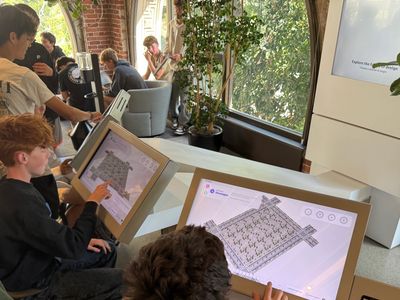 Students interact with digital design interfaces in a bright, modern learning space.
