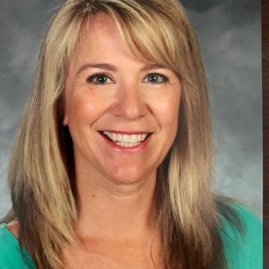 Smiling woman with blonde hair wearing a green top.