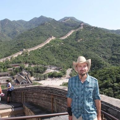 Tourist posing on the Great Wall of China with mountainous backdrop.