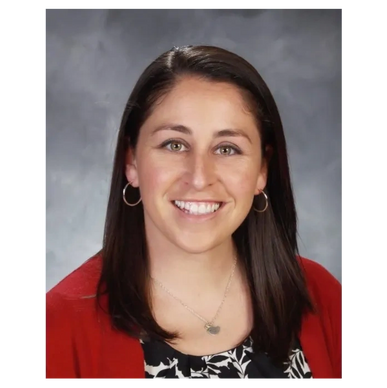 Smiling woman with dark hair wearing a red cardigan and hoop earrings.