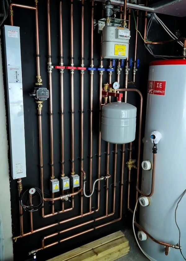 Neatly organized copper piping system with gauges and valves in a utility room.