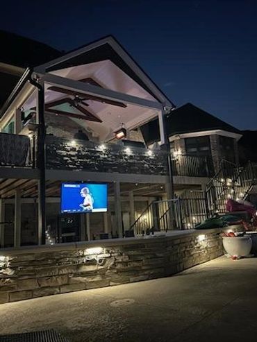 Night deck with Trex, Westbury railing, Coronado stone, and outdoor TV—built to entertain.