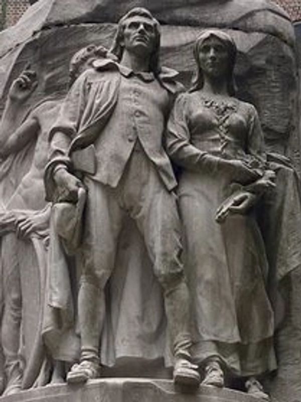 Stone statue of a man and woman in historical attire.