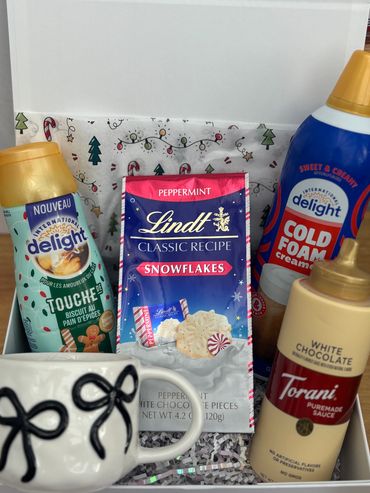 Holiday-themed coffee gift set with creamers, white chocolate sauce, and peppermint white chocolate snowflakes.