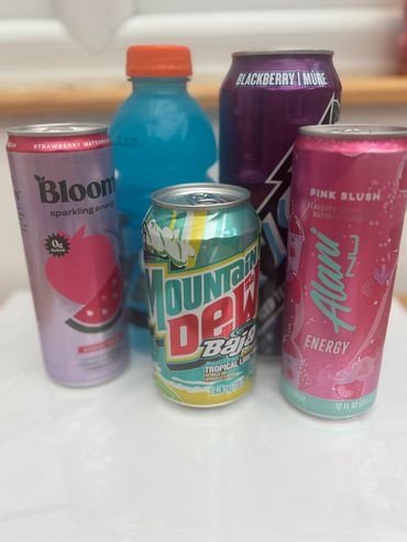 Variety of colorful energy drinks and soda cans on a white surface.