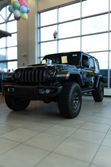 Black Jeep Wrangler inside a showroom with balloons.