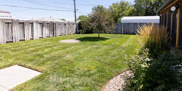 Backyard with green lawn and wooden fence.