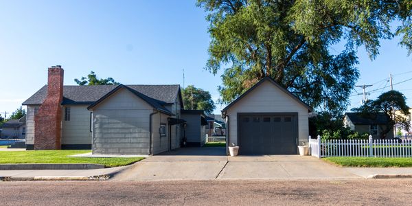 A house with a detached garage and a white picket fence.