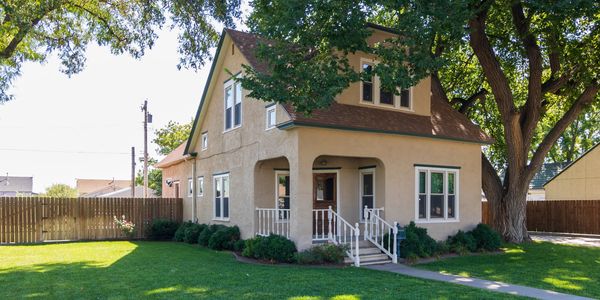Cozy two-story house with large tree and green lawn.