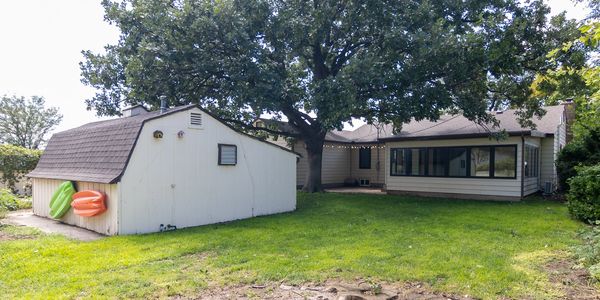 Backyard with green grass, tree, and shed.