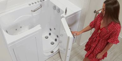 Woman opening door for walk in bathtub for safe bathing of seniors and elderly.