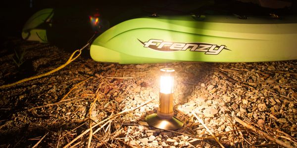 UCO Candle Lantern with Survival Stand attached, on shore with boat in summer