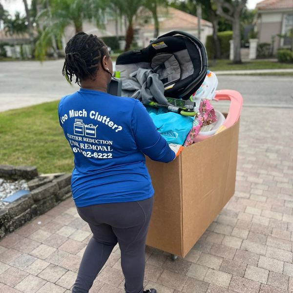 Worker removing a large box of household items from a garage.