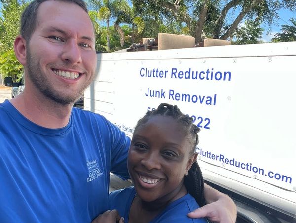 Husband and wife coworkers posing in front of the work truck, smiling, in matching uniforms.