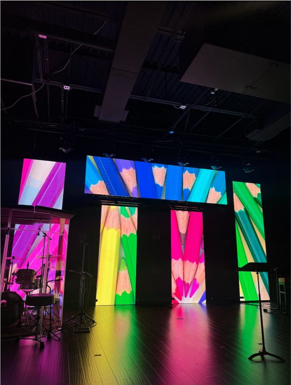 Colorful pencil display on stage screens with musical instruments.
