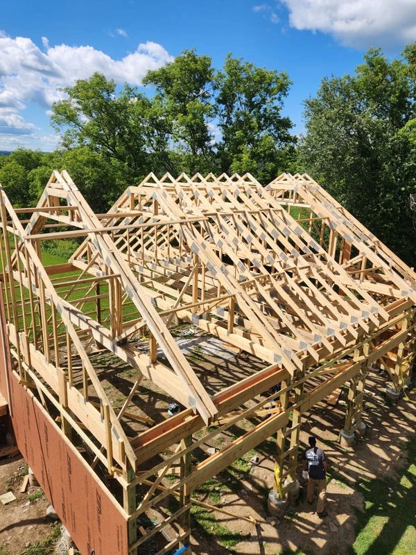 Wooden house frame under construction on a sunny day.