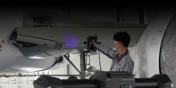 Técnico inspecciona alas de avión con equipo láser.