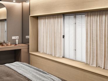 Cozy bedroom corner with beige curtains and a wooden window seat.