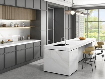 Modern kitchen with marble island and grey cabinetry.
